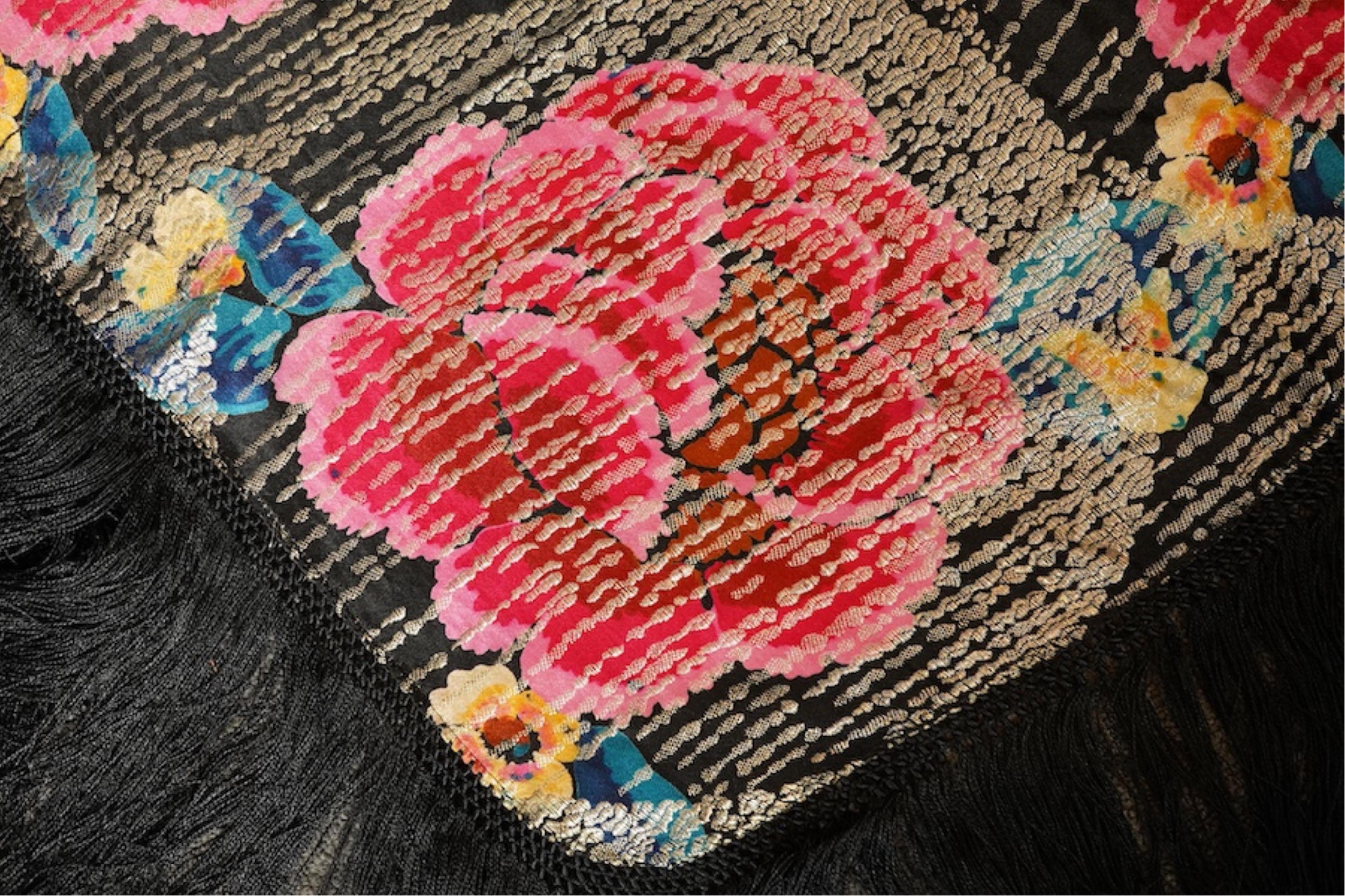 A 1930's ‘jazz age’ black and coloured silk lame evening shawl. Woven with giant pink and red roses and silver thread stripes, edged with long silk fringing. 118cm x 123cm. Condition - colours and silk strong. Fringing g